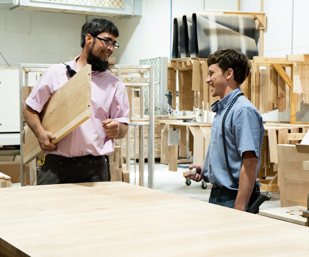 Staff discussing Amish quality furniture order in woodshop.